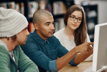 Group of college students look at a computer monitor in a college library